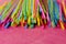 Colorful single use disposable plastic straws on pink surface