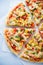 Colorful sliced pizza with mozzarella cheese, chicken, sweet corn, sweet pepper and parsley close up top view