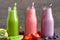 Colorful smoothie drinks in bottles with a straw and fresh fruits and berries