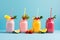 Colorful smoothies in glass jars with straws and fruits on blue background, Fresh fruit smoothies in glass jars with straws on