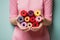 Colorful spools of threads in hands heart shape on the pastel pink background. Womanly hobby. Sewing concept. Empty place for text