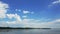 Colorful spring summer landscape on river with beautiful clouds in the sky, shooting from a car that goes on the road along