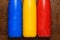 Colorful stainless thermos bottles on a wooden table sprayed with water.