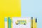 Colorful stationary school supplies on yellow and blue trending background and painted yellow bus in the center of note with a