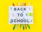 Colorful stationery on yellow background with lightbox saying back to school text