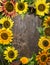 Colorful sunflowers frame on rustic wooden background, top view