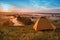 Colorful sunrise over tourist tent in camp among meadow