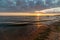 colorful sunset over calm sea beach with dark blue water and dramatic contrasty clouds