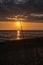 colorful sunset over calm sea beach with dark blue water and dramatic contrasty clouds