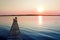 Colorful sunset over the lake with a pier. A lone fisherman is fishing on the pier.