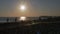 Colorful sunset. Sea view with waves and foam, pier and pebble beach. Silhouettes of happy floating people in the sea.