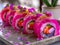 Colorful Sushi Roll Platter with Pink Wraps, Sesame Seeds, and Fresh Vegetables, Japanese Cuisine on Trendy Background