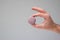 Colorful sweet macaroon cookie held in hand by Caucasian male hand. Close up studio shot, isolated on gray background