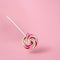 Colorful swirling lollipop on pink background.