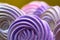 Colorful swirls meringue on yellow background. Sweet candy dessert purple color made from sugar and proteins