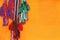 Colorful tassels of a hippie belts on orange background.