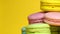 Colorful tasty macaroons rotating on the yellow background