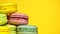 Colorful tasty macaroons rotating on the yellow background