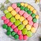 Colorful tasty macaroons on wooden table with flowers, a french sweet delicacy, macaroon texture.