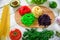 Colorful tasty pasta on board and raw vegetables on rustic table. Flat lay. Top view