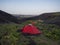 Colorful tents in Botnar campsite at Iceland on Laugavegur hiking trail, green valley in volcanic landscape among lava