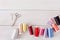 Colorful thread spools and scissors on wooden table flat lay