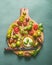 Colorful tomatoes with basil leaves and mozzarella in bowl with olives oil on round wooden cutting board, top view. Italian food