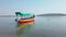 Colorful tourist boat in sea. Bright tourist boat with person on board floating on calm sea water against cloudless blue sky on