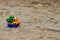 Colorful toy truck on the sand outdoors. Horizontal shot.