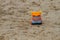 Colorful toy truck on the sand outdoors. Horizontal shot.