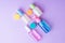 Colorful travel size bottles with cosmetics on lavender background.