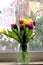 Colorful tulips in vase on windowsill, cheerful home decor