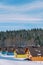 Colorful two-story cottages in a snowy resort village at the edge of a coniferous forest