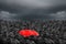 Colorful umbrella in mass of black umbrellas.