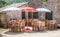 Colorful umbrellas covering the dining tables. Checkered pattern cloth lining the wood. Vacant lot offering food for customers. Co