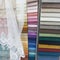 Colorful upholstery fabric samples, material, textile, curtain.  a white curtain, a machine embroidery, falls freely over them