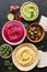 Colorful varied hummus, caponata, olives, pita and pomegranate on a dark rustic background. Top view, flat lay. Mediterranean food