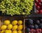 Colorful variety of fruits waxy green grapes, plums, lemons, peaches in cartons