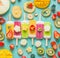 Colorful various Ice cream popsicles with fresh sliced fruits and berries ingredients on light blue background, top view, flat la