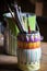 Colorful vase holding artist brushes in a studio setting.