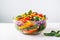 a colorful vegan salad in a glass bowl on a white table