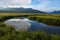 Colorful view on Rabbit Creek in Potter Marsh  with blue skies and reflections of clouds in the river water.