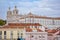 Colorful walls of the buildings of Lisbon, with orange roofs and the Church of Sao Vicente of Fora in the background. Sunny day