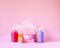 Colorful washcloth, plastic travel bottles and bars of soap on a soft pink background. Accessories for body care and hygiene