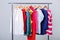 Colorful womens clothes on hangers on rack on gray background. w