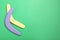 Colorful wooden boomerangs on green background, flat lay. Space for text