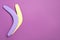 Colorful wooden boomerangs on purple background, flat lay. Space for text