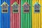 Colorful wooden houses for insects hanging on multicolored wooden fence.