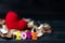 Colorful of wooden love text with aroma dried flowers and leaves. yarn red heart on the dried flowers on the black wooden table.
