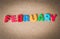 Colorful wooden word FEBRUARY on cork board with selective focus